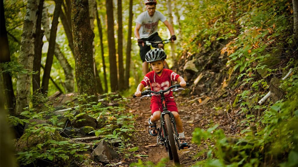1920x1080 photo of boy child and father riding bikes through a trail in the woods
