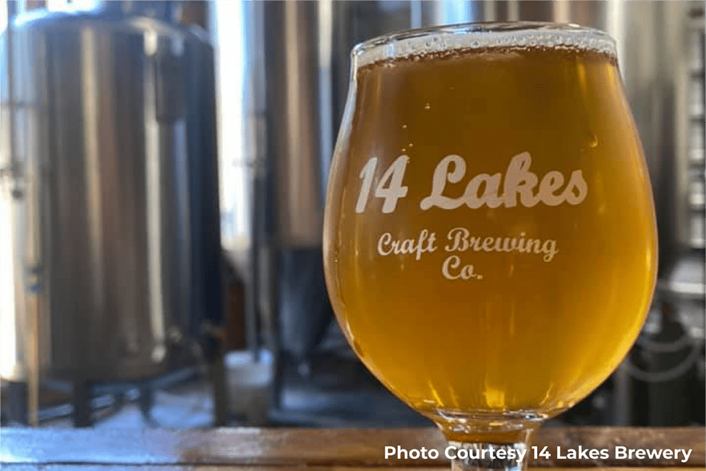 1200x800 photo of glass of beer from 14 Lakes Brewery in front of metal still