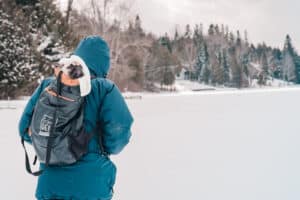 Photo of a person hiking on the ice during winter carrying a backpack with a little dog in it at Ruttger's Bay Lake Resort