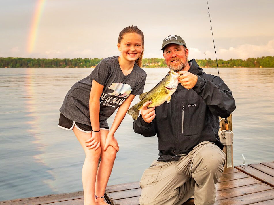 Square Photo of a dad and daughter fishing off a dock at Craguns Resort with a rainbow in the background