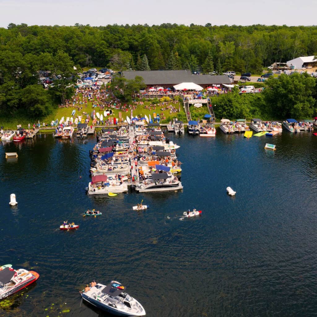 Square photo of Moonlite Bay in the summer during the Antique Boat Show showing dozens of boats in the lake