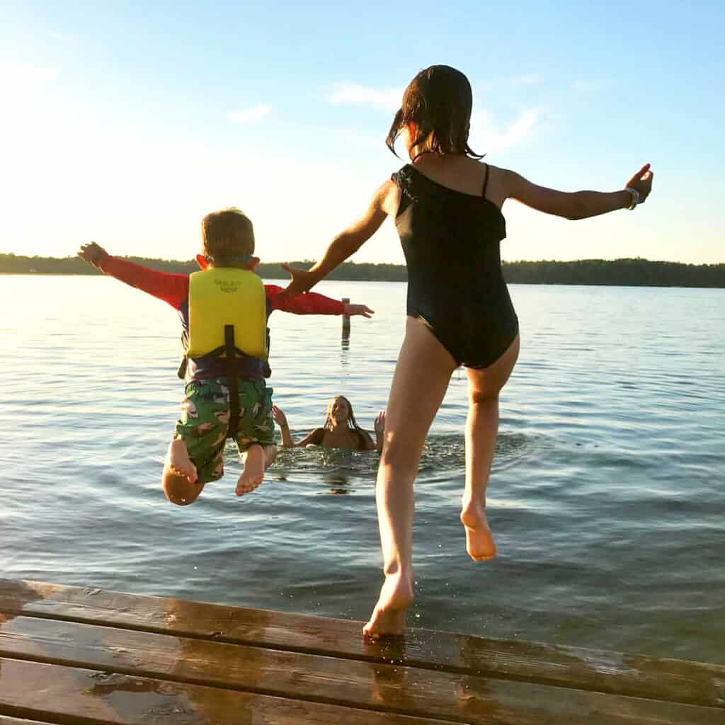 Square photo of kids jumping off dock and into a lake at Eagles Nest Resort