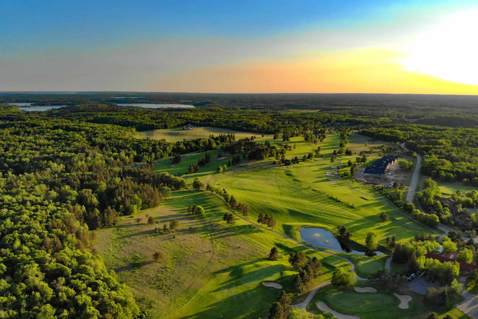 1920x1280 aerial photo taken at sunset of golf course next to forest