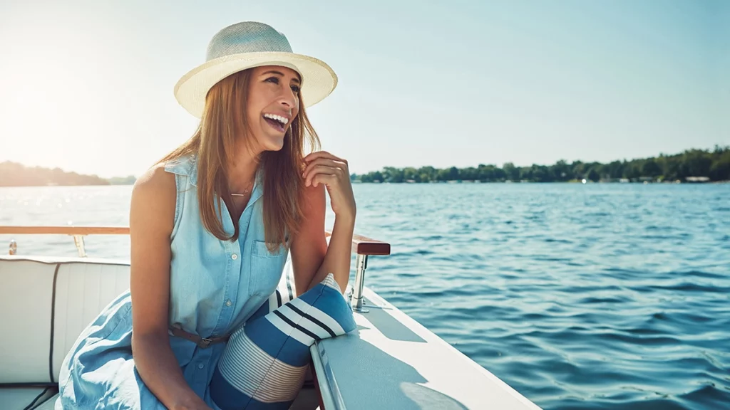 Photo of a woman smiling on a boat in a lake on a sunny summer day
