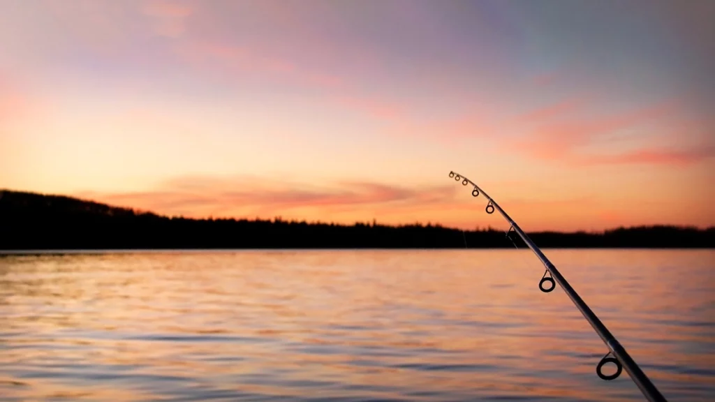 Photo of fishing pole and lake from boat at sunset