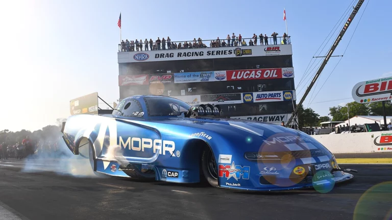 Photo of blue race car with crowd in background at Brainerd International Raceway on sunny summer day