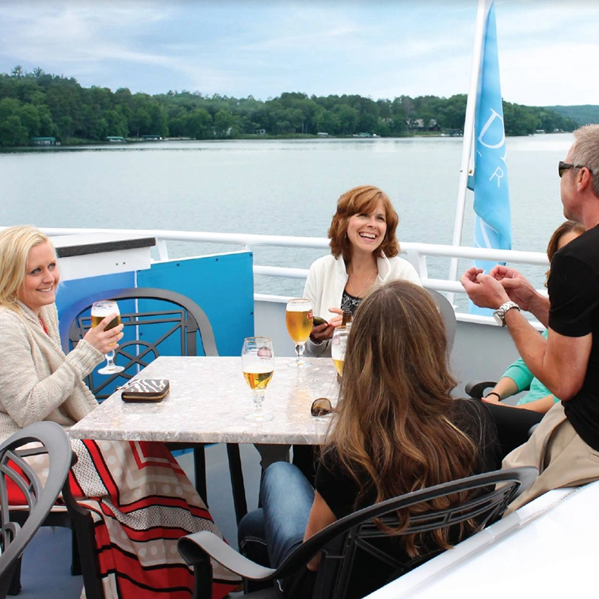 Photo of a group of women smiling and having drinks on board Gull Lake Cruises on a summer day