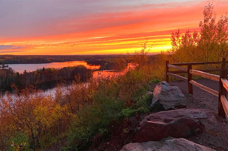 Cuyuna Country Overlook at the Cuyuna Country State Recreation Area showing an outcropping of a trail overlooking a lake during an orange sunset