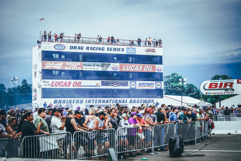 Photo of a crowd of people at BIR NHRA Nationals and a tall announcer stand in the background on a summer day