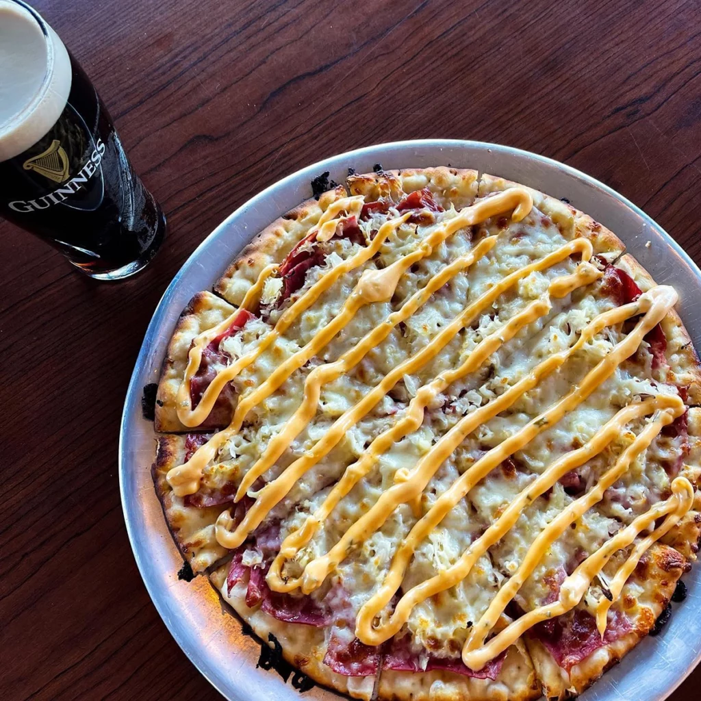 Photo of a pizza and a tall glass of beer sitting on a plate on a table at Rafferty's Pizza in Nisswa copy