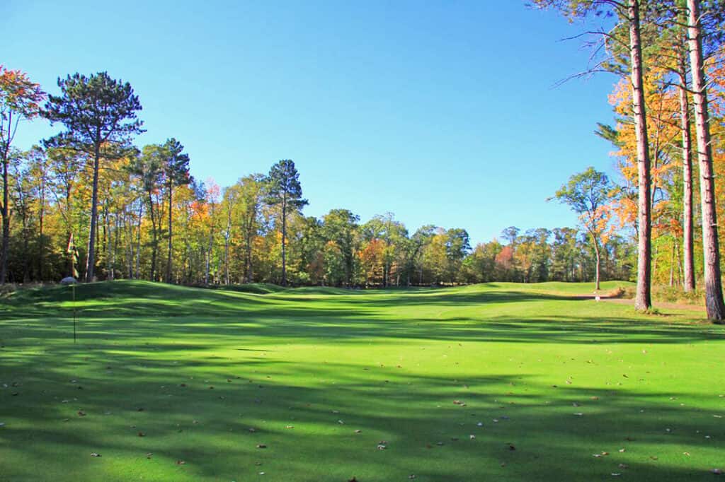 Crosswoods Golf Course on a sunny fall day with blue skys and trees with orange leaves and green grass