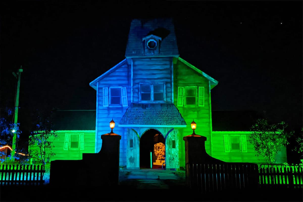 Photo of a haunted house at night at Paul Bunyan Land that is lit up with blue and green lights