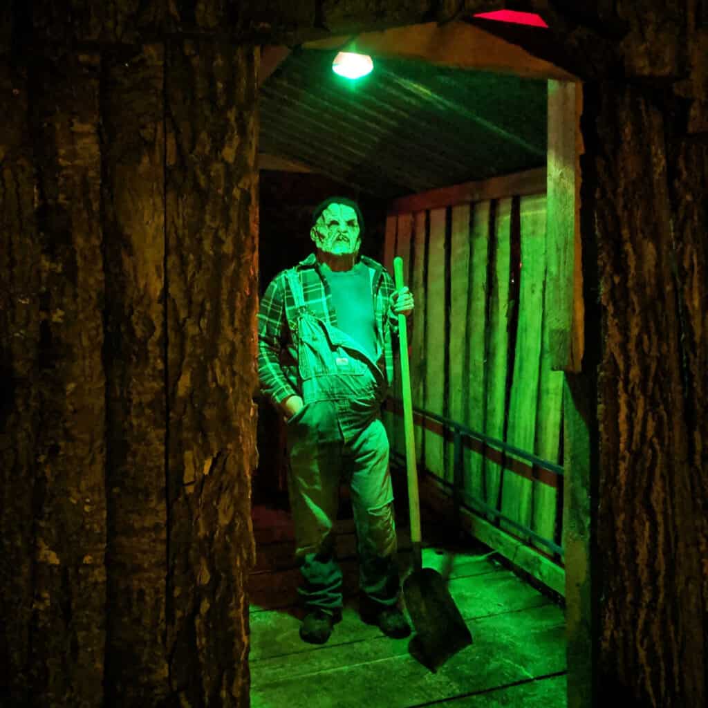 Photo of the Haunted Hidden Hollows at Paul Bunyan Land showing a scary man dressed up in a scary outfit in a haunted house at night
