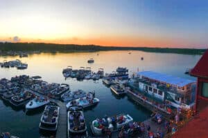 Photo from Breezy Point Resort showing the lake next to the resort filled with boats and pontoons full of people parked at the large docks at sunset on a beautiful summer evening at sunset
