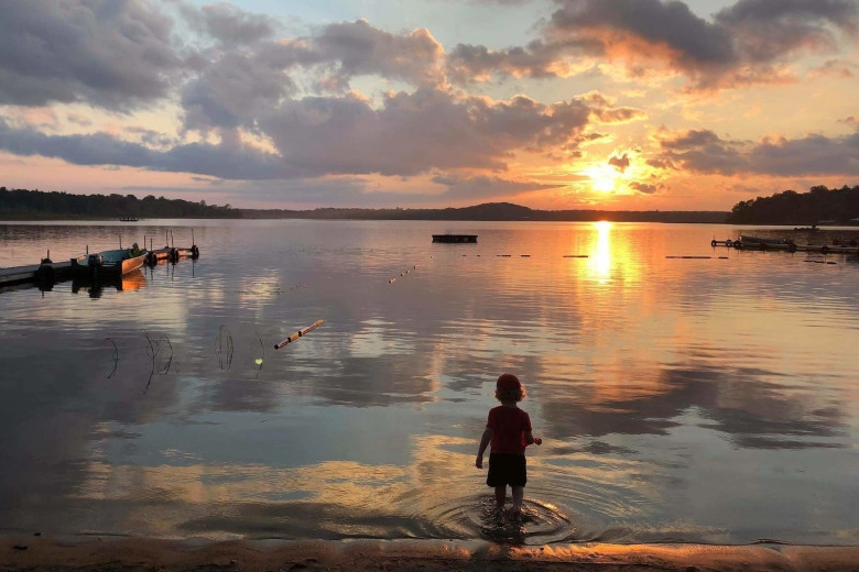 Photo of a small boy playing in the water of a lake at sunset at Upper Cullen Resort and Campground copy