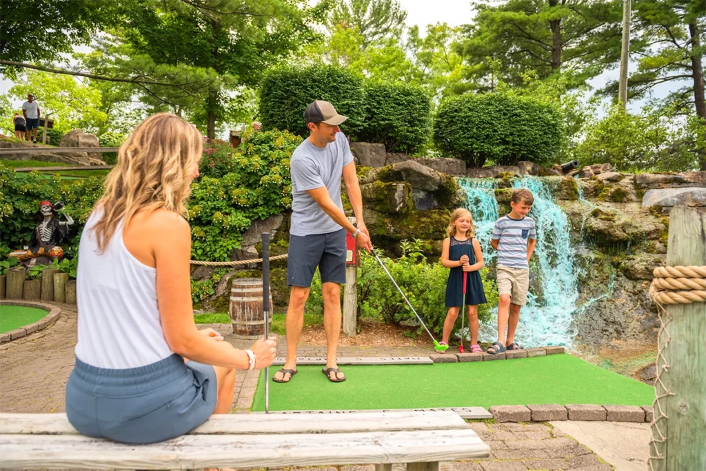 Pirates Cove Adventure Golf photo of a mom and dad golfing with their two small children, a boy and a girl copy