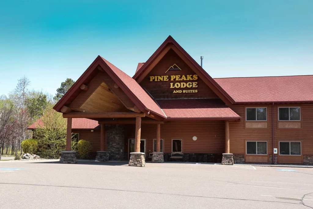 Photo of Pine Peaks Lodge and Suites that is a hotel built in a cabin style on a spring day with a blue sky background copy 2