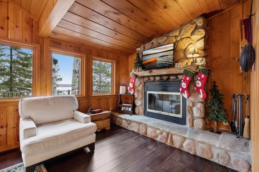 Photo of the interior of a large cabin with a stone wood burning fire place on a sunny day of a Crosslake Minnesota getaway on Trout Lake part of the Whitefish Chain of Lakes