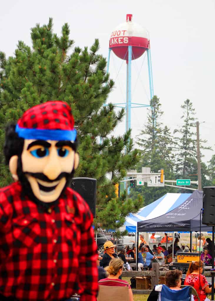 Bean Hole Days in Pequot Lakes showing person dressed up as Paul Bunyan with the crowd of people in the background and the bobber water tower