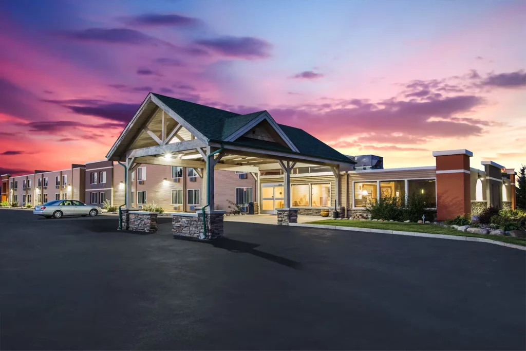 Photo of Americinn Baxter showing the exterior of the hotel with a purple and pink sunset in the background